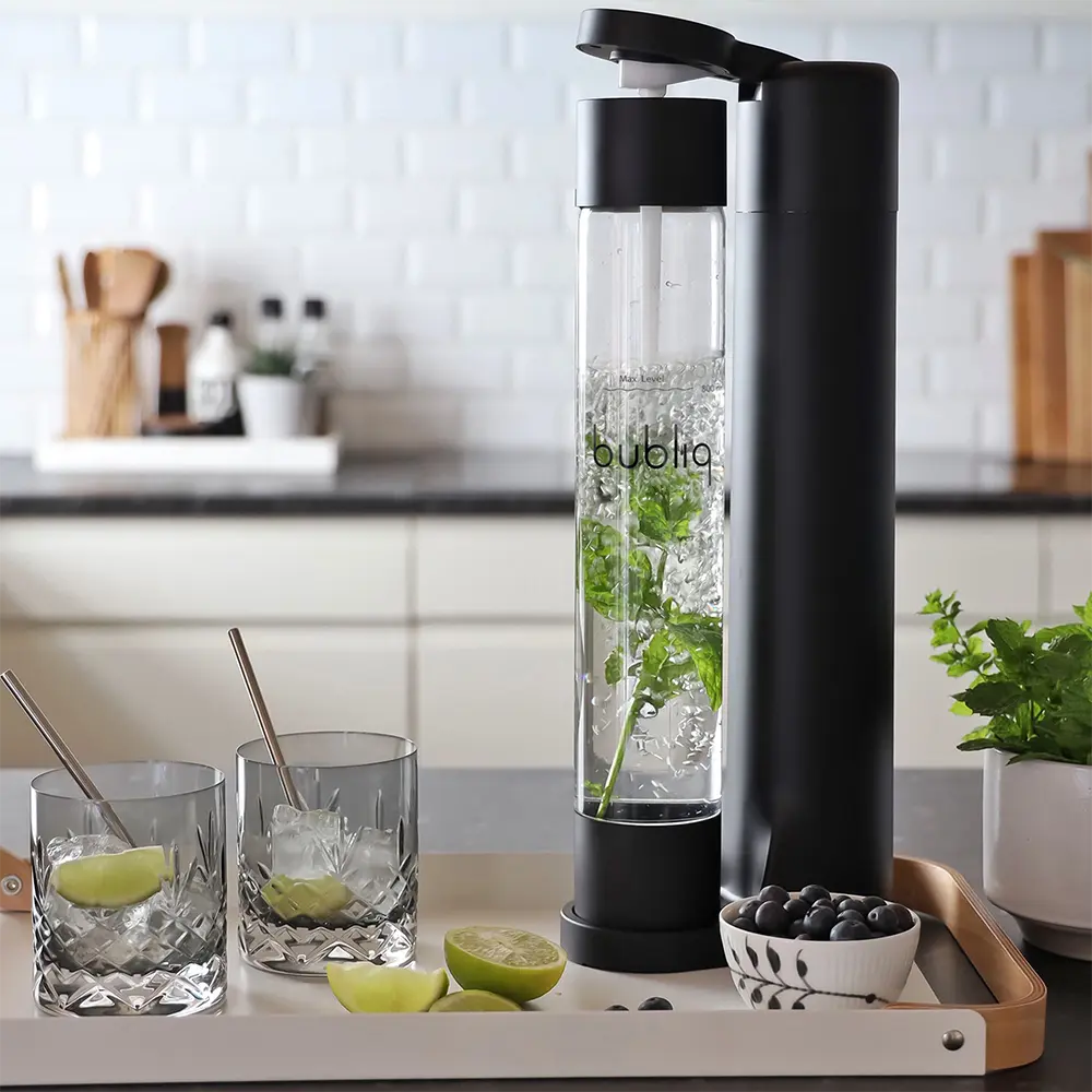 bubliq sodavandsmaskine i matsort på køkkenbakke, to glas og friske skiver af lime