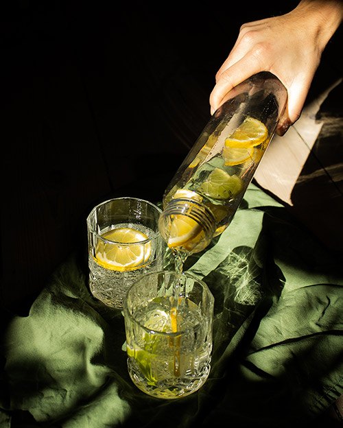 mattschwarze bubliq-Flasche, die frisch zubereitetes Sprudelwasser in zwei Gläser gießt