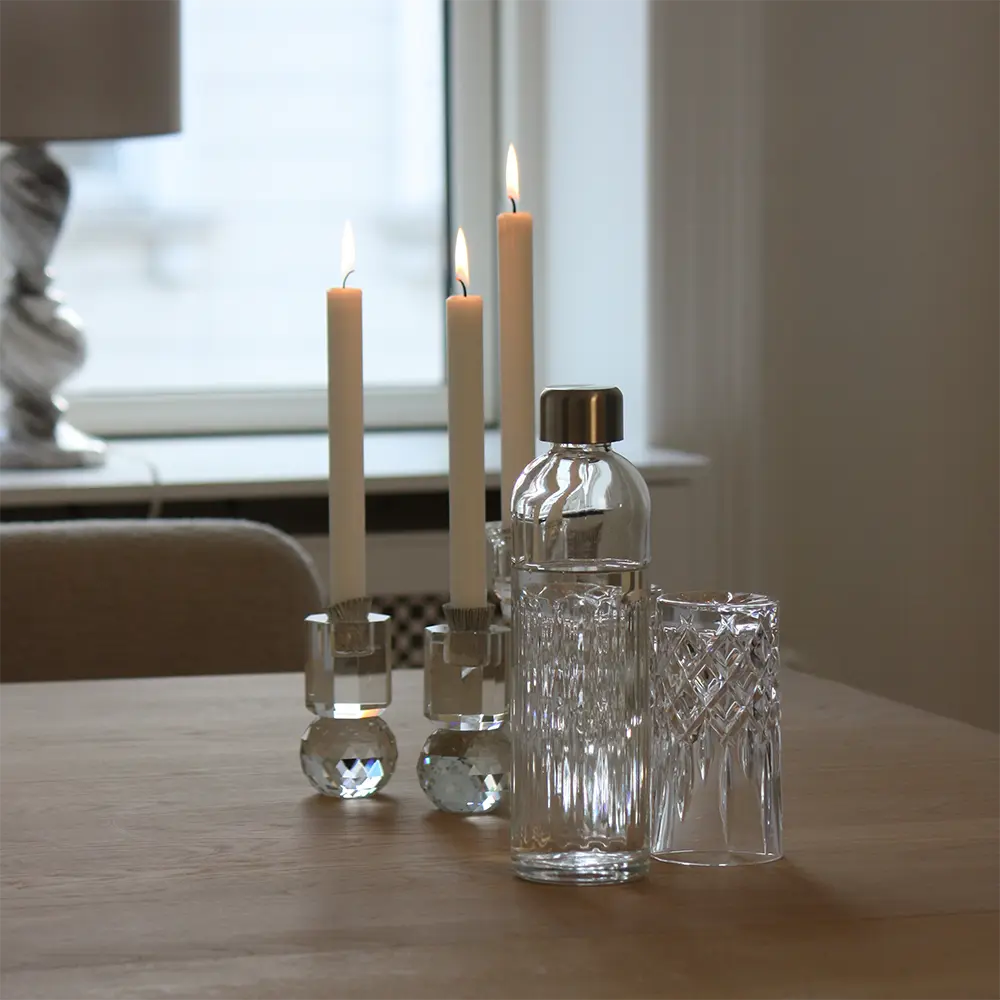 Glasflaske til bubliq glass carbonator på et bord med drikkeglas og stearinlys