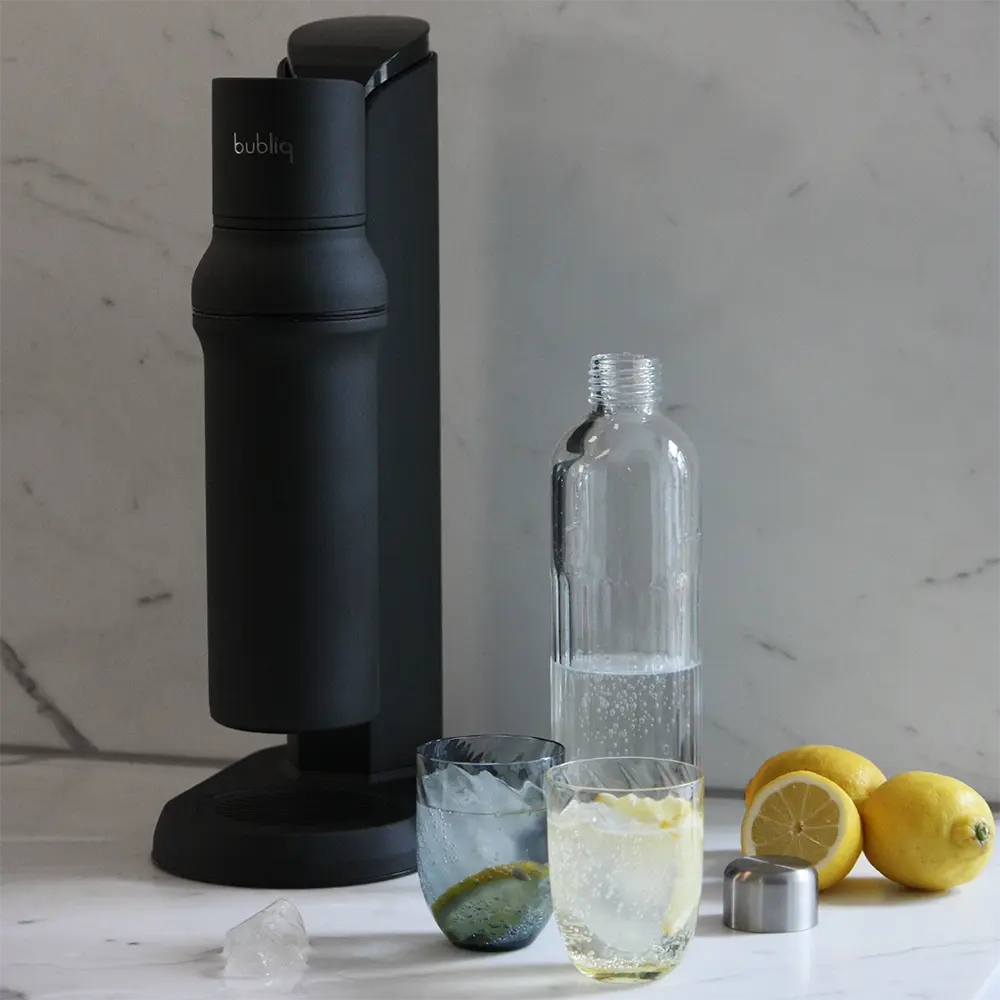 bubliq sodavandsmaskine på marmor køkkenbord med glasflaske og to glas med danskvand