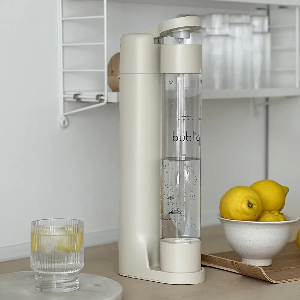 Beige sodavandsmaskine fra bubliq på køkkenbord med glas med danskvand