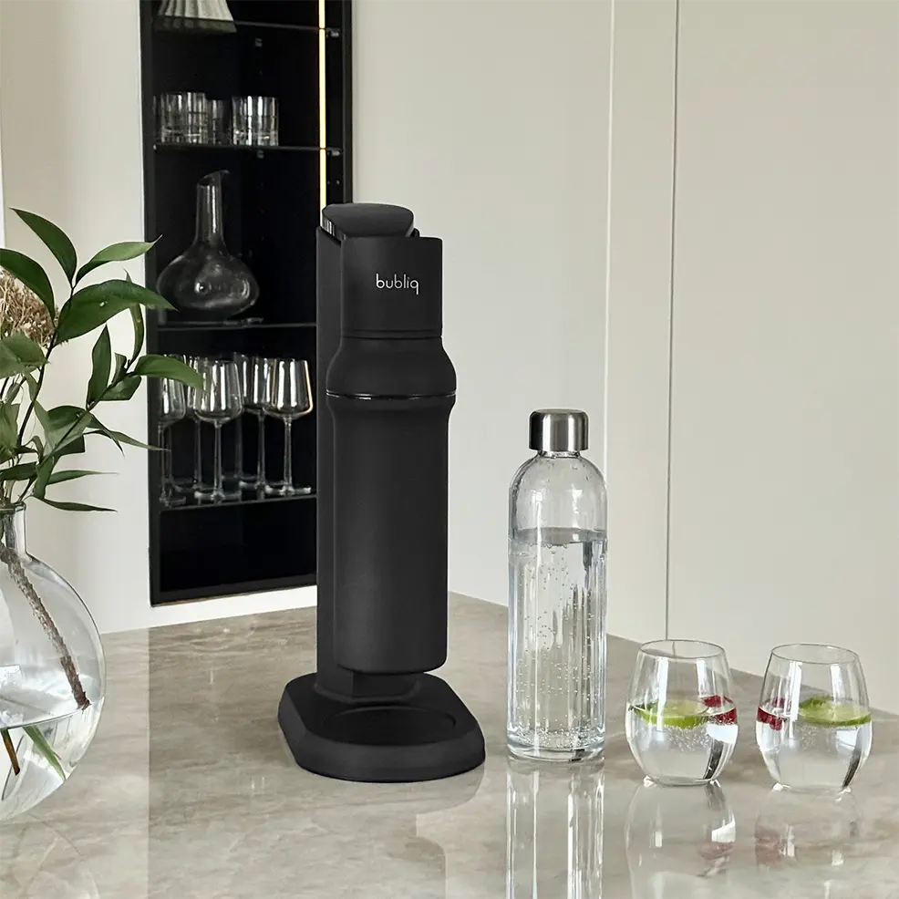 Matsort sodavandsmaskine med glasflaske fra bubliq på bord